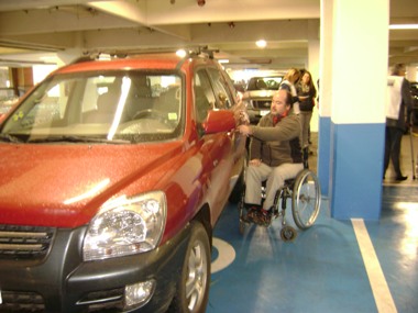 Persona en silla de ruedas ingresa a su automovil estacionado en el lugar para personas con discapacidad