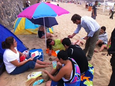 Francisco lazo entrega material de difusión a familia que veranea en playa Amarilla.