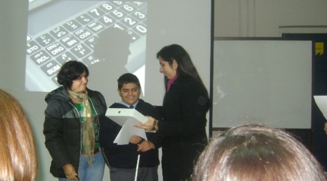 La encargada de educación de la Dirección Regional Metropolitana entregando calculadora a uno de los jóvenes beneficiados.