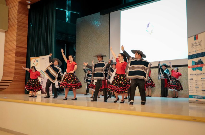 Jóvenes de la fundación bailando vestidos con trajes típicos chilenos. 