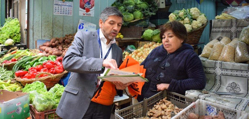 Seremi de Desarrollo Social, Ricardo Figueroa, entrega folletería a locatarios del mercado El Cardonal. 