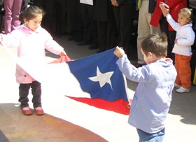 Dos niños del jardín infantill Bambi que ejecuta un proyecto del Programa de Apoyo a Estudiantes con Discapacidad, sostienen la bandera de Chile.