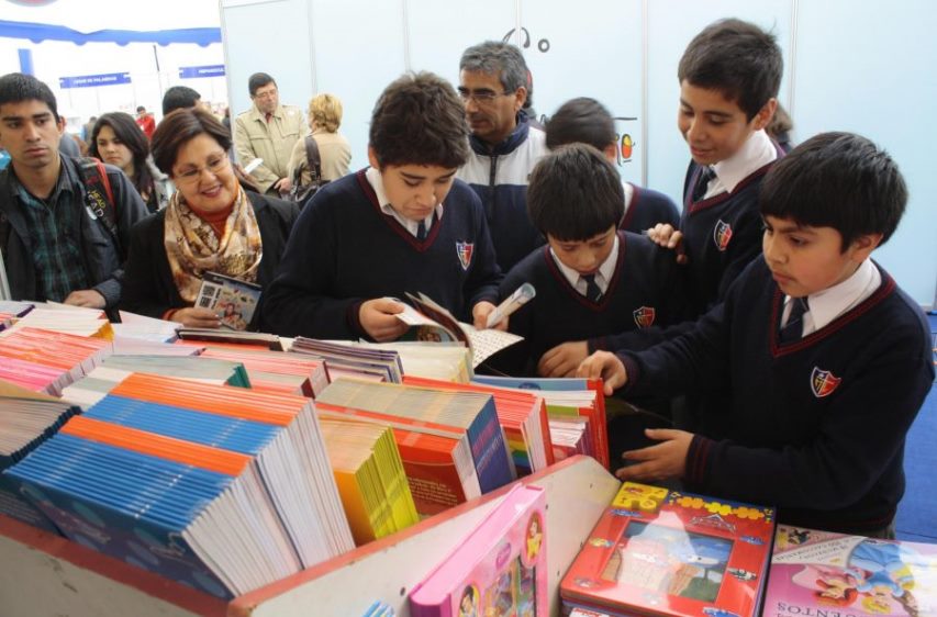 Niños revisando libros en una feria de libros. 